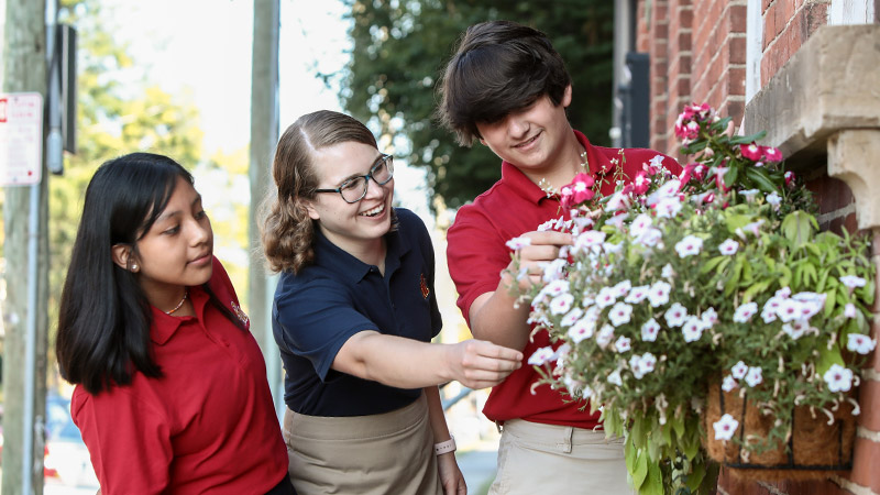 Two female and one male student looking at flowers outside